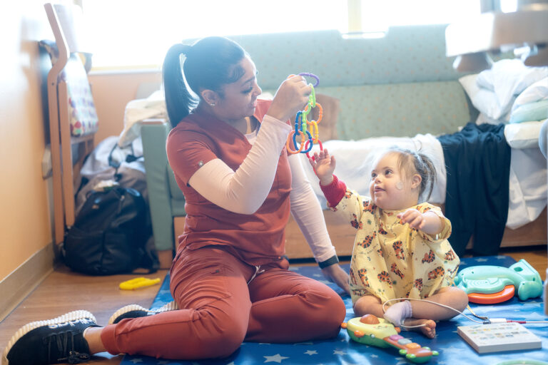 a nurse plays with a young girl with down syndrome