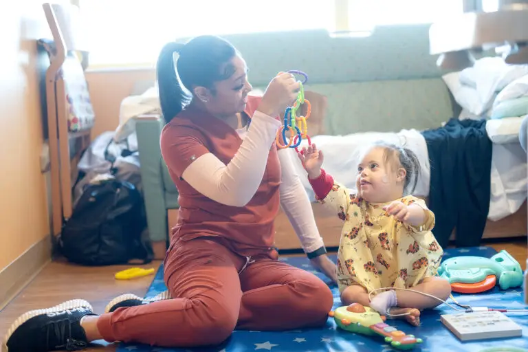 a nurse plays with a young girl with down syndrome