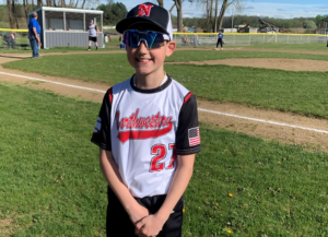 Maxton standing in his baseball uniform in front of a baseball field