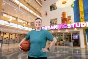 Recreation Therapy specialist, Tayler Tadrick, holding a basketball and smiling in the Atrium at UPMC Children's