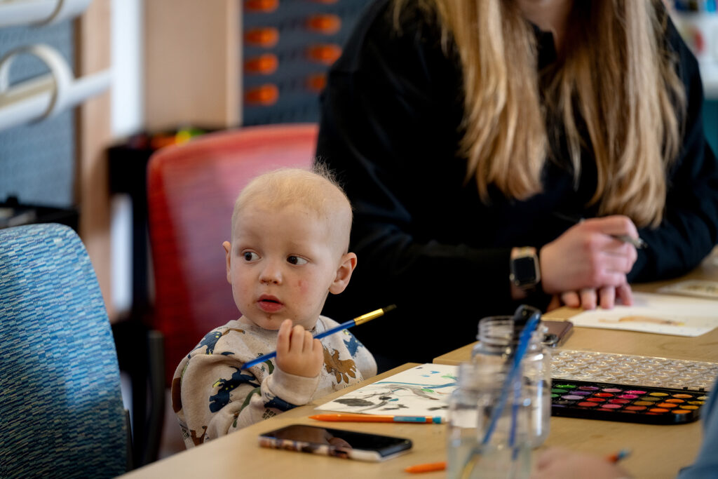 a patient at UPMC Children's holds a paintbrush in an art therapy session