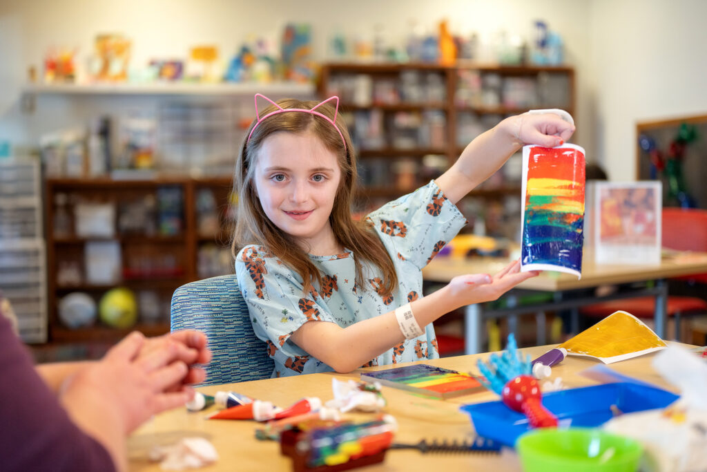 a girl holding up a painting she made